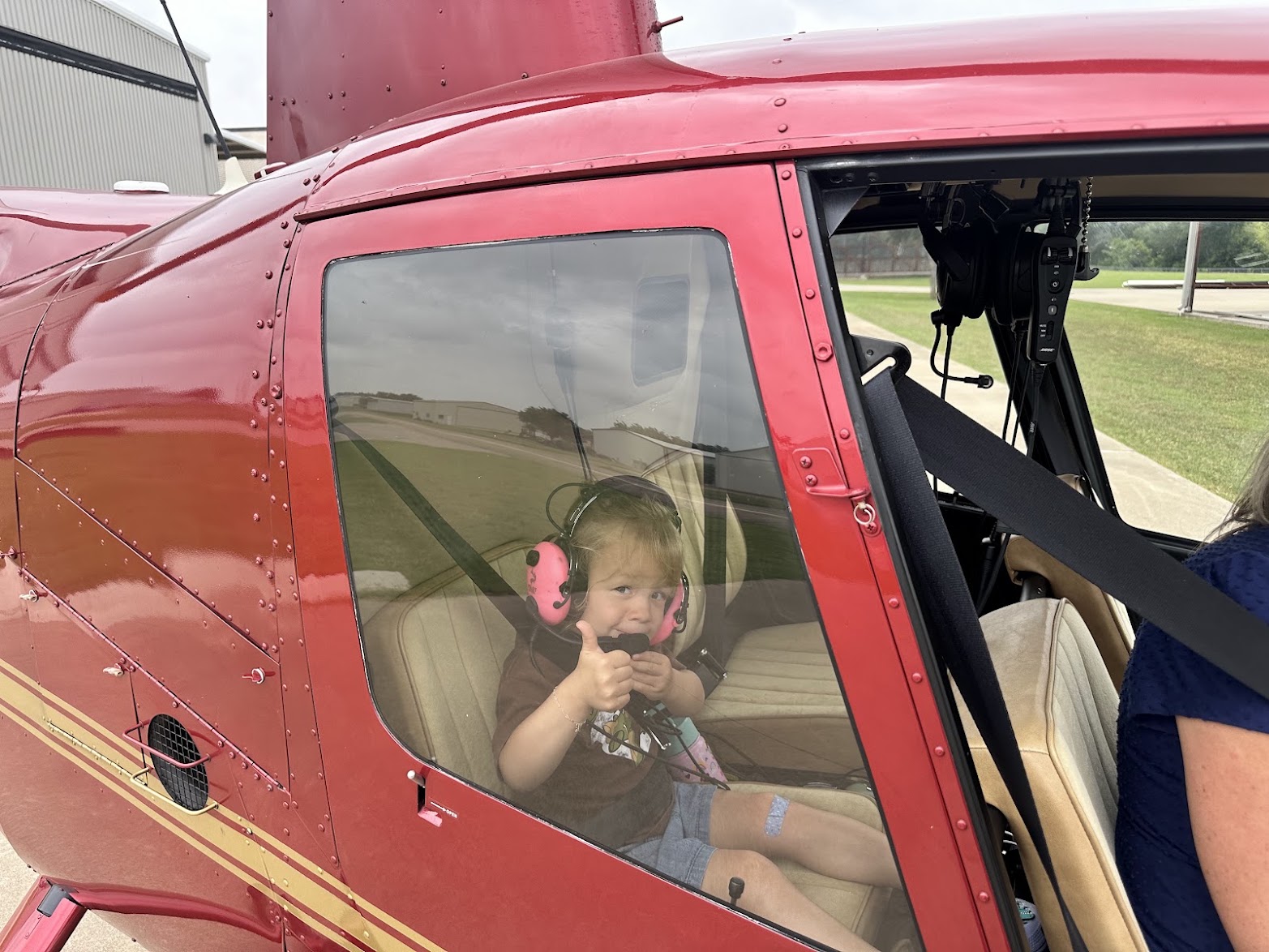 A young Young Eagles passenger giving a thumbs up from the cockpit of a helicopter